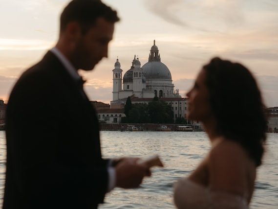 Casal em silhueta contra o horizonte de Veneza ao pôr do sol.